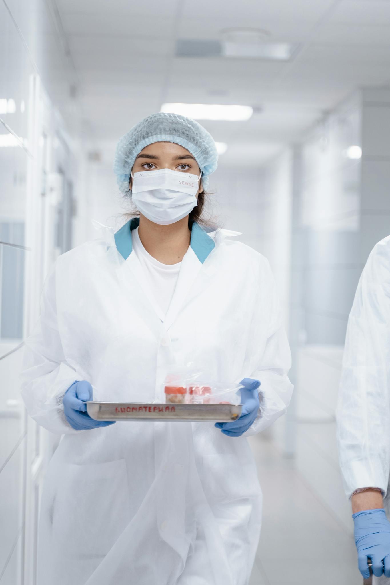A woman in protective gear holding samples in a laboratory setting.